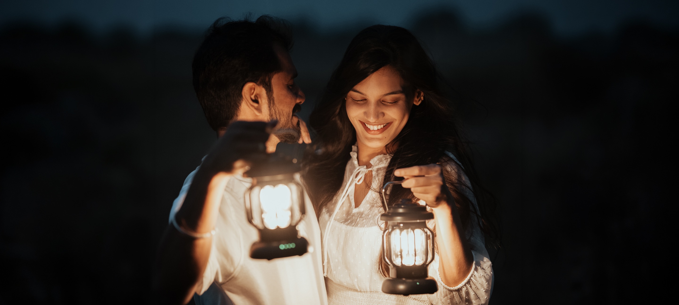 Couple sharing a laugh in the dark, each holding a glowing lantern