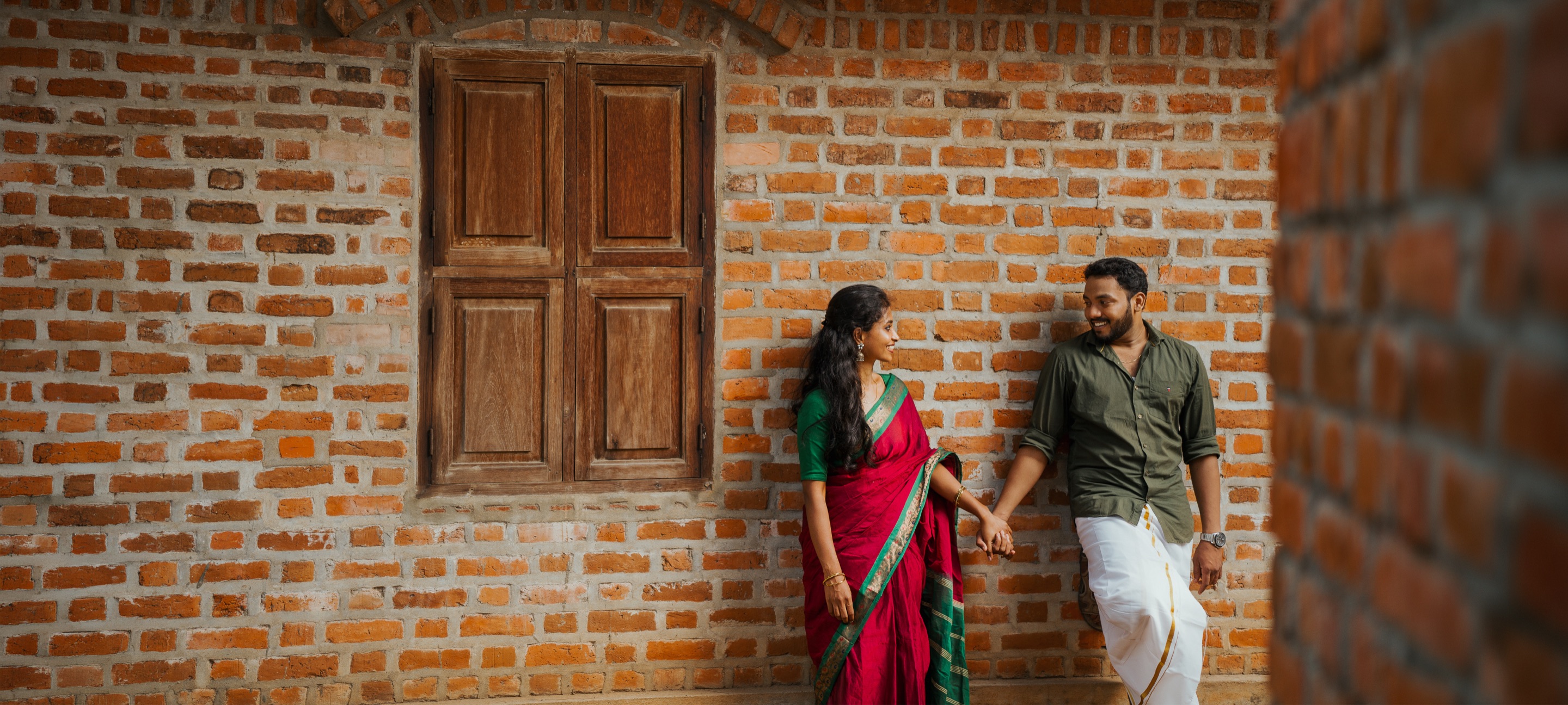Couple holding hands against a brick wall