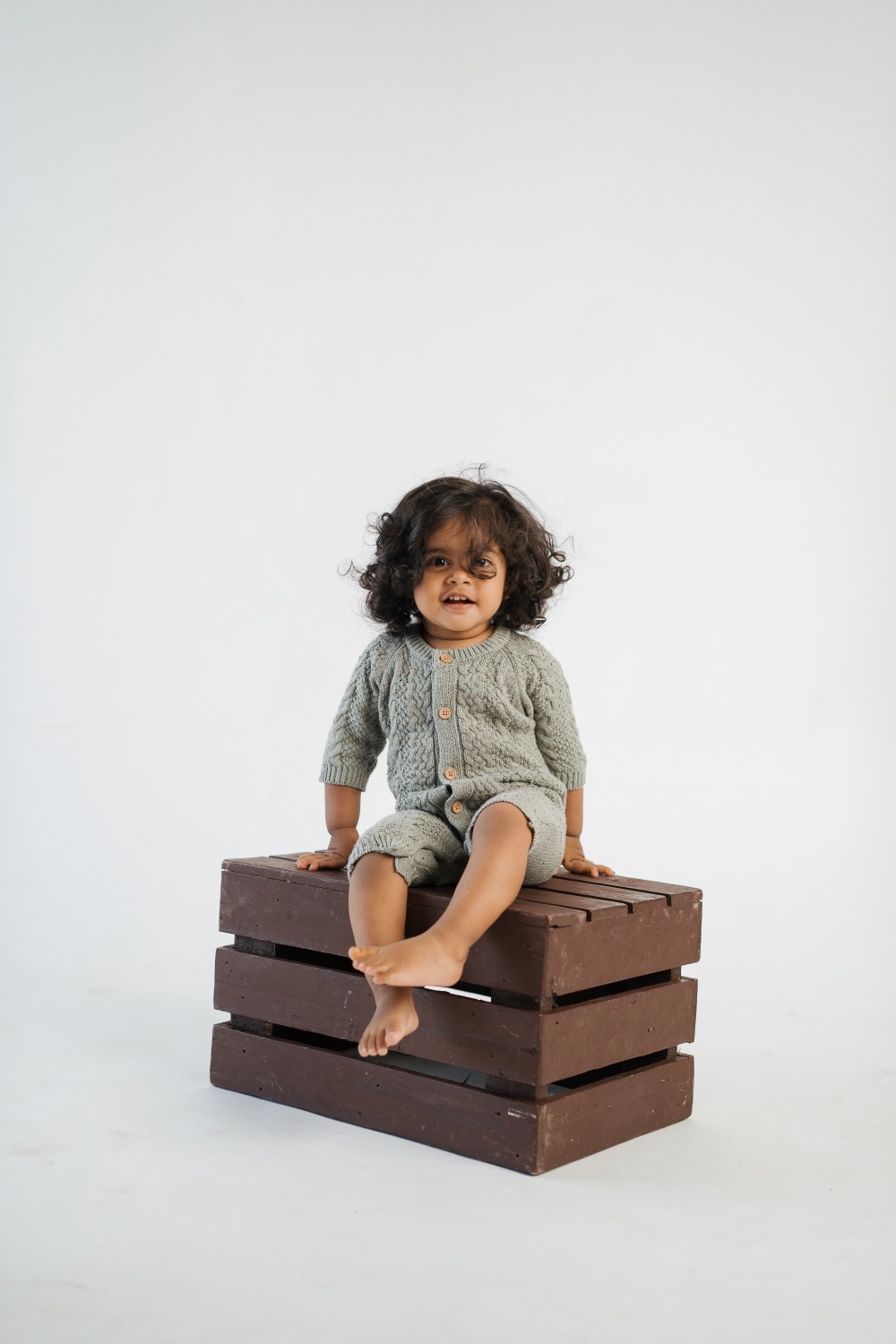 Toddler seated on a wooden crate in studio