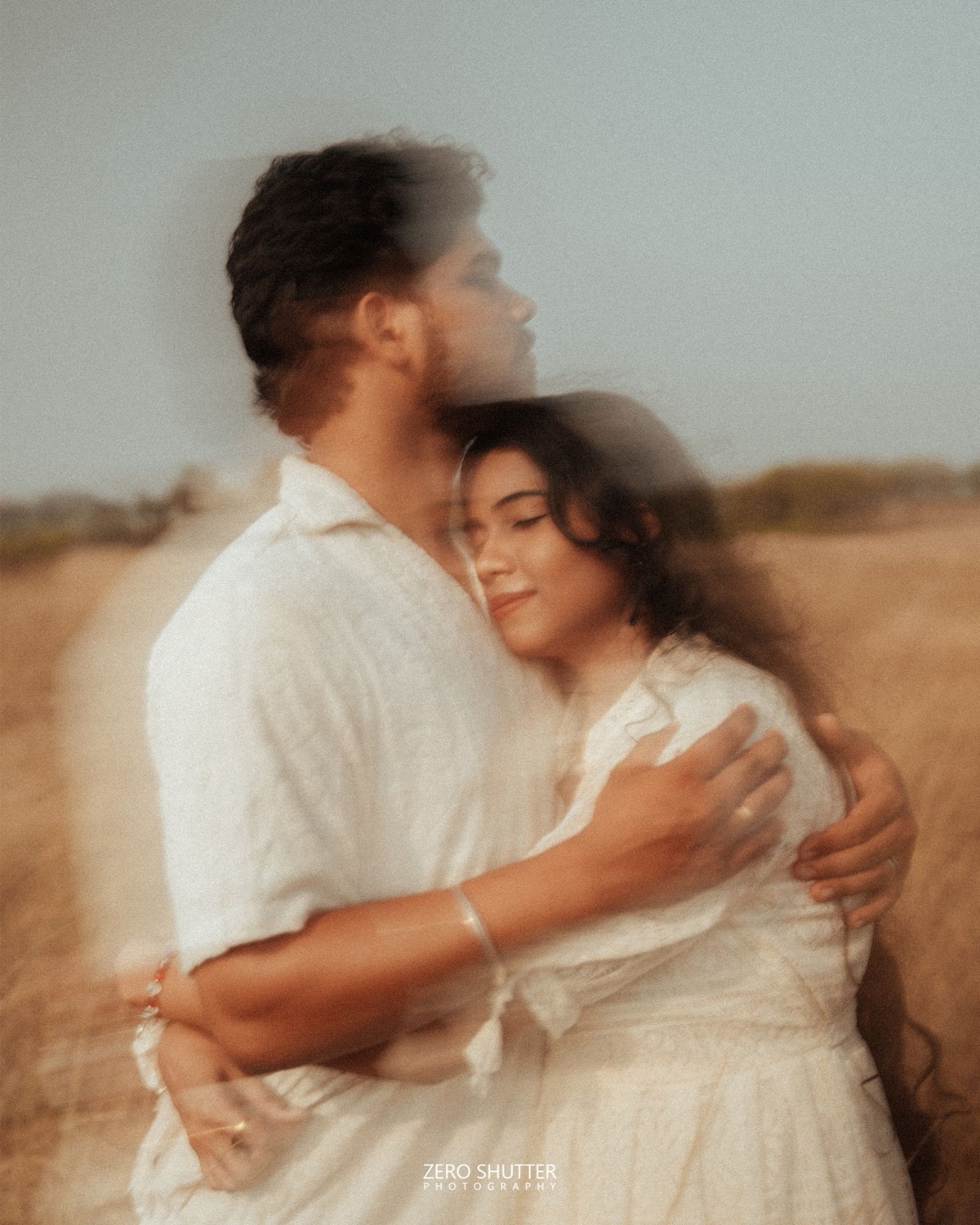 Couple embracing in a soft, dreamy motion-blur frame in a golden field