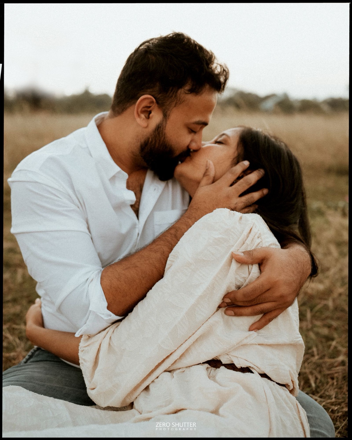 Couple kissing in a golden field at sunset