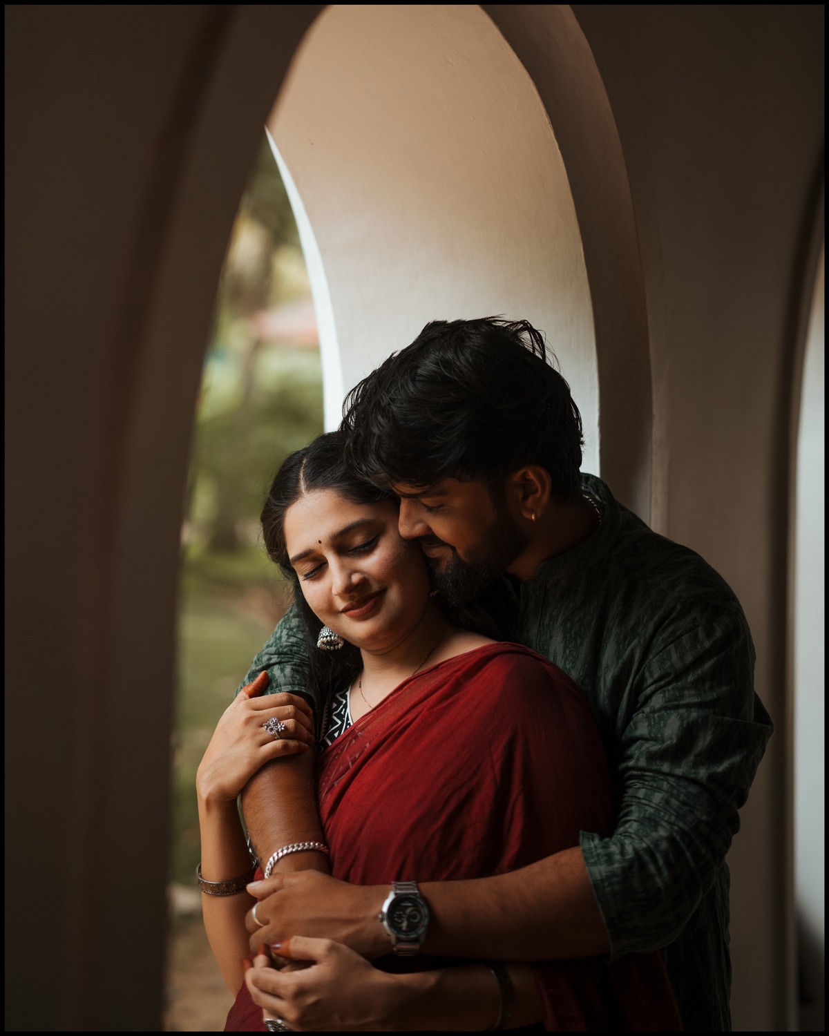 Husband embracing his wife from behind beneath a heritage archway