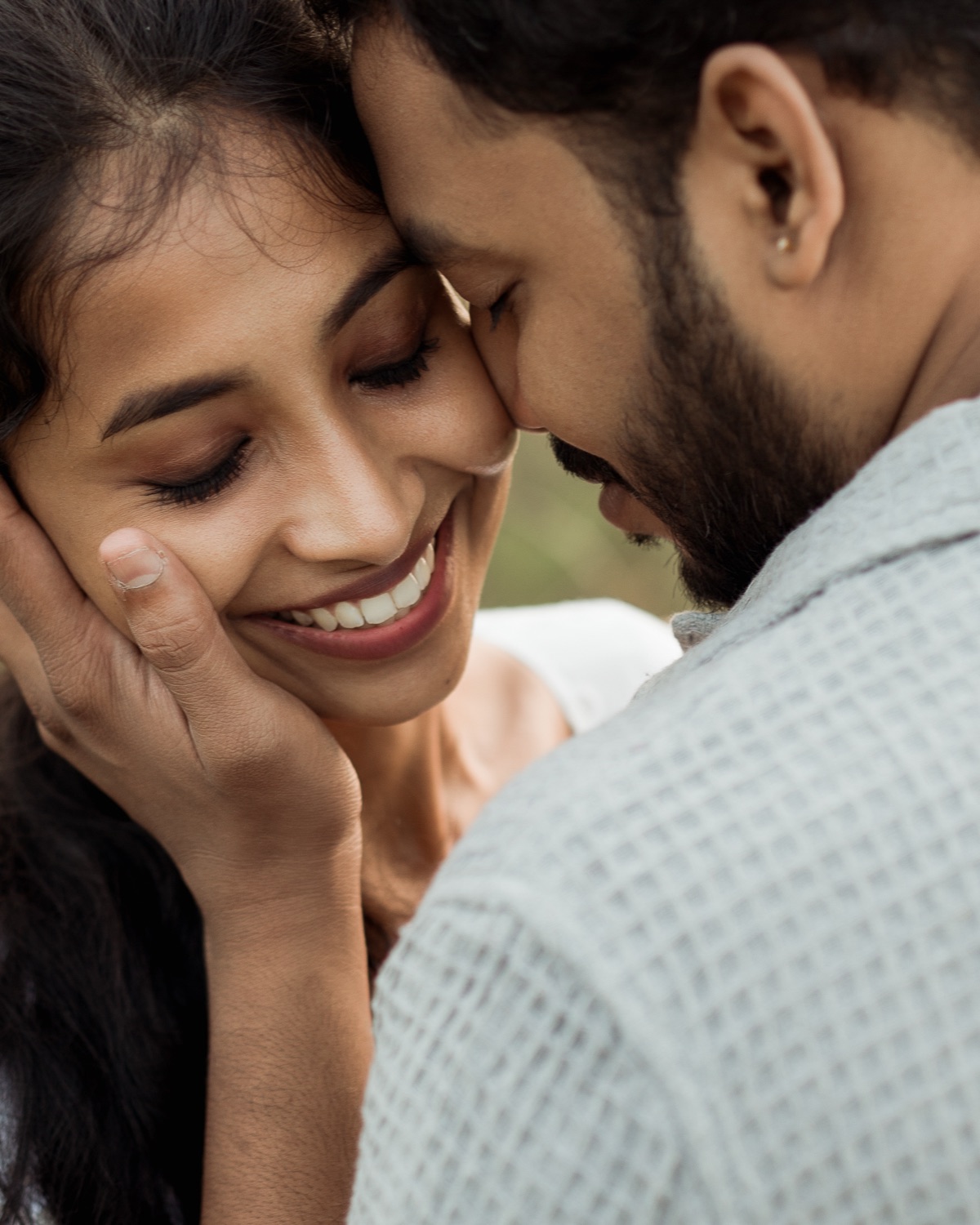Couple close together, his hand resting against her cheek