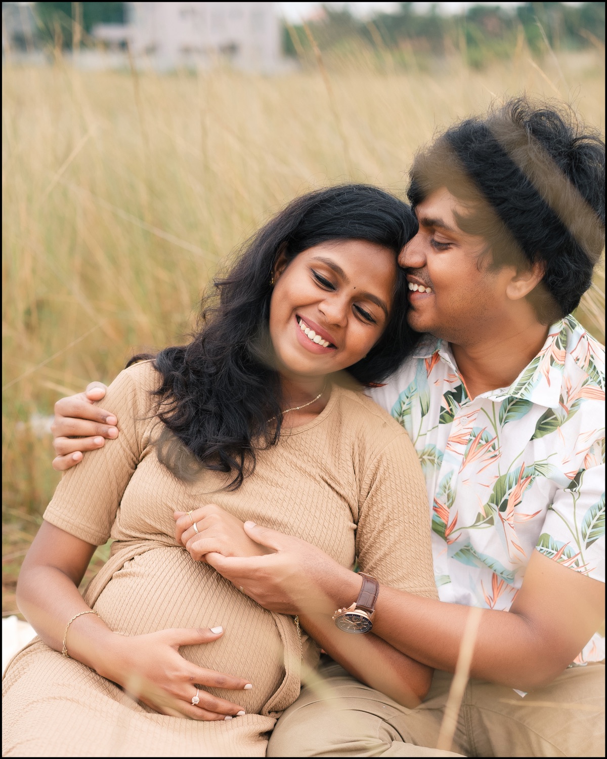 Expecting parents sharing a close embrace in a golden field