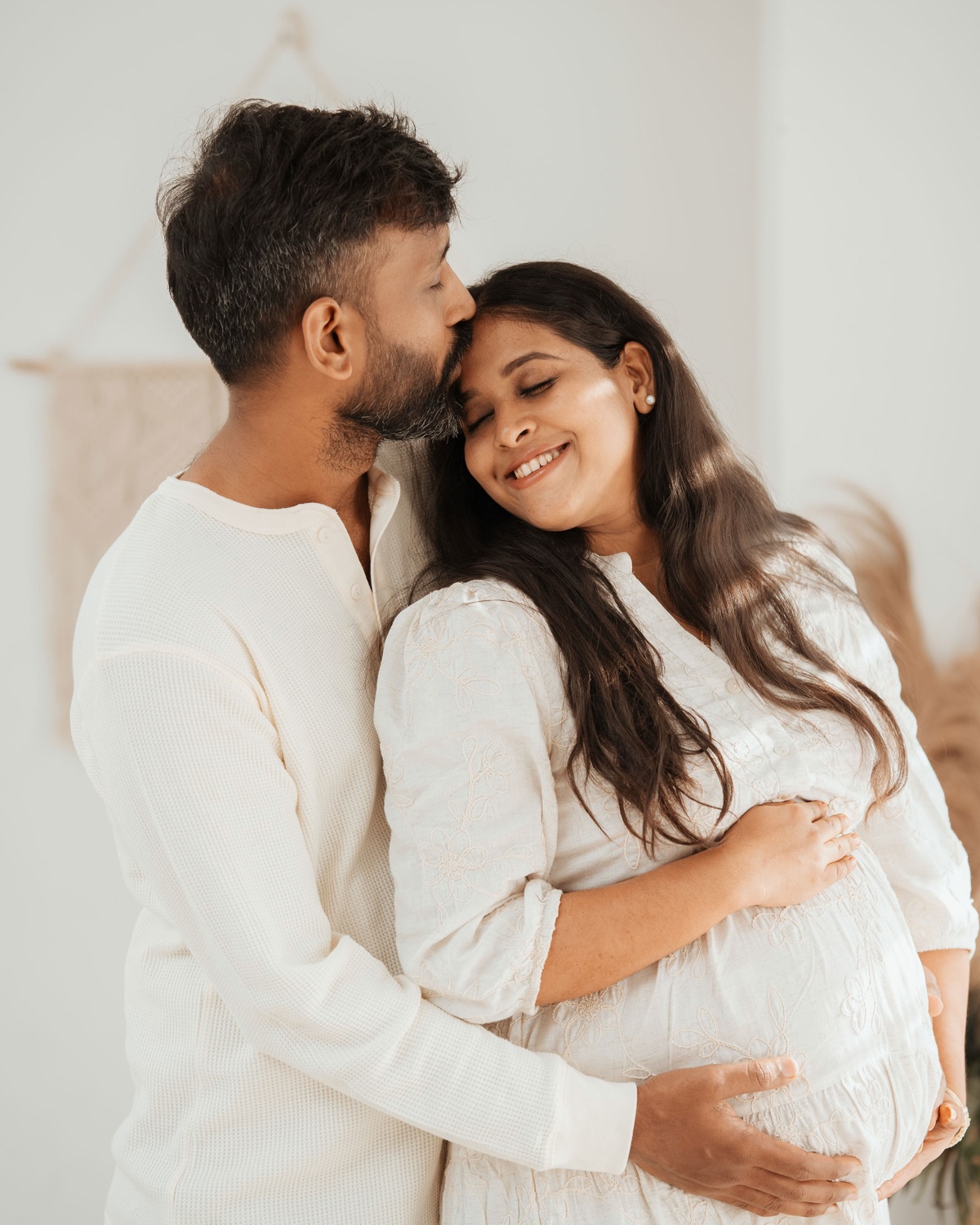 Husband kissing his wife's forehead while cradling her bump