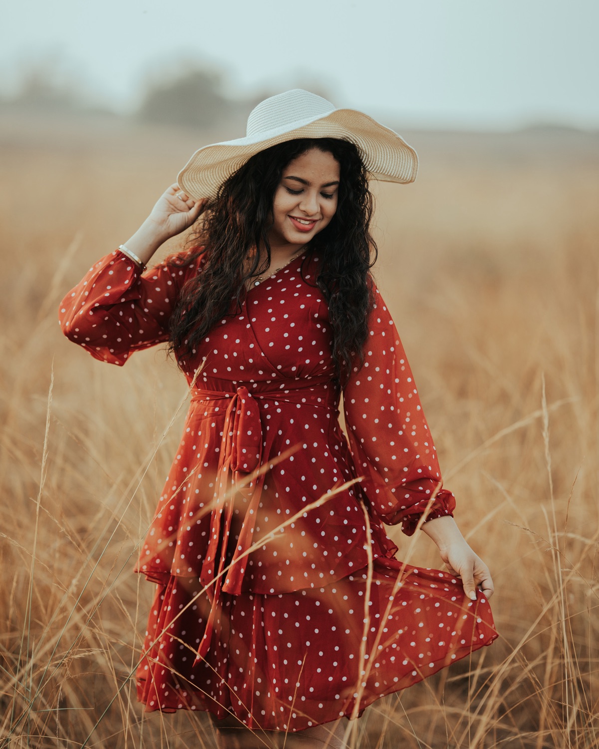 Portrait in a red dress and straw hat in a golden field