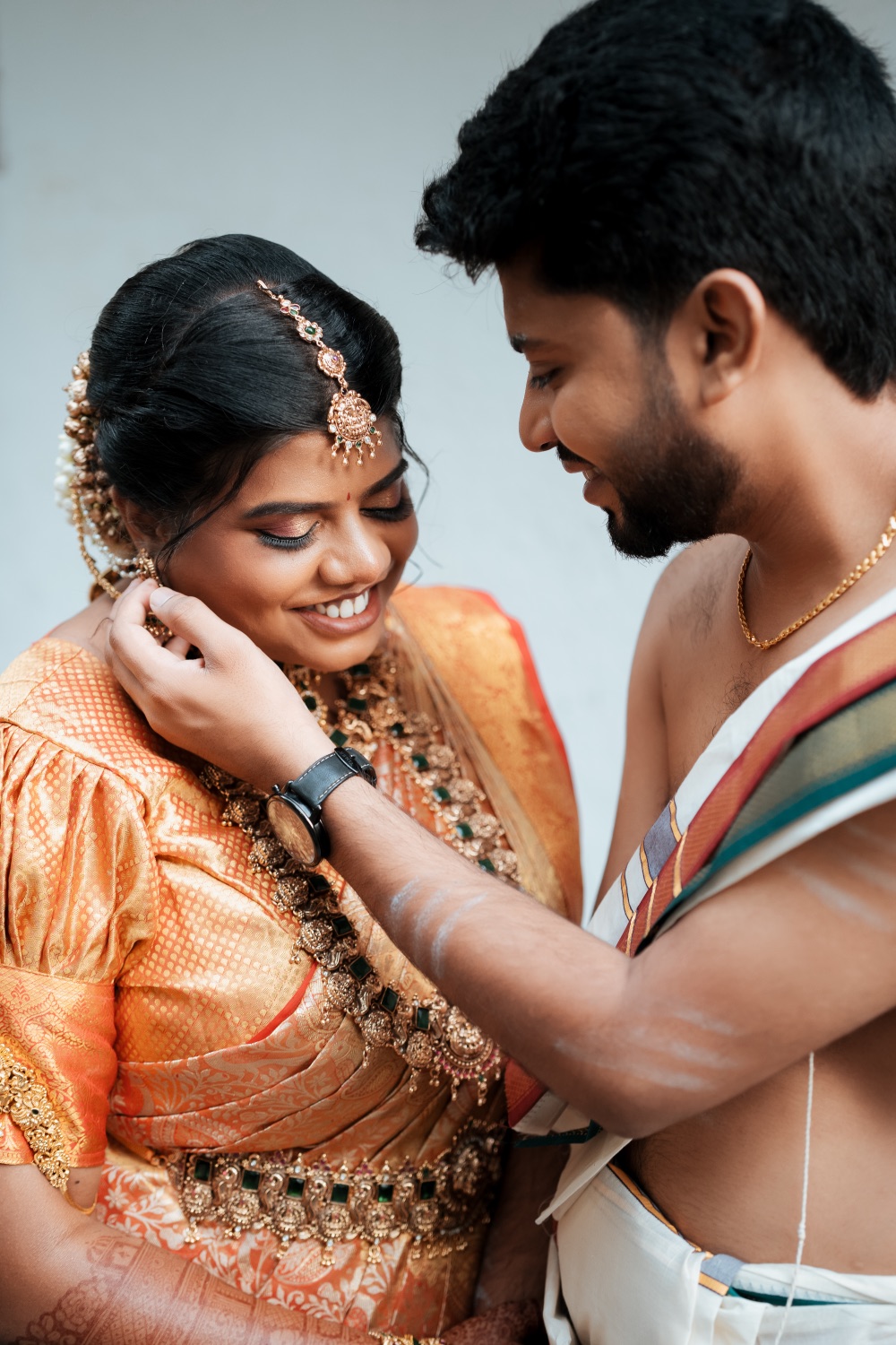 Groom fastening his bride's jewellery before the ceremony